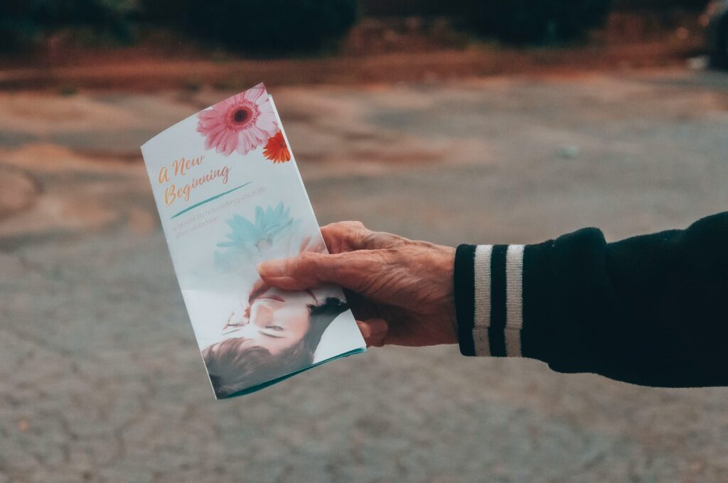 person holding white and pink floral card