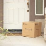 brown cardboard box beside white wooden door