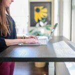 woman in black shirt sitting at the table using macbook