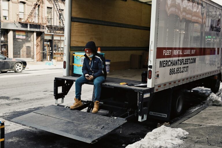 man in blue denim jeans sitting on black and white trailer