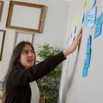 a woman writing on a wall with sticky notes