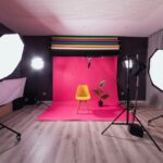 a photo studio with a pink backdrop and a yellow chair